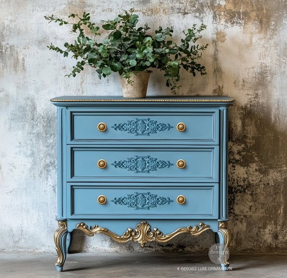 A vintage 3-drawer dresser is painted light blue with gold accents and features ReDesign with Prima's Luxe Ornamenta Decor Poly Casting in the center of its drawers.