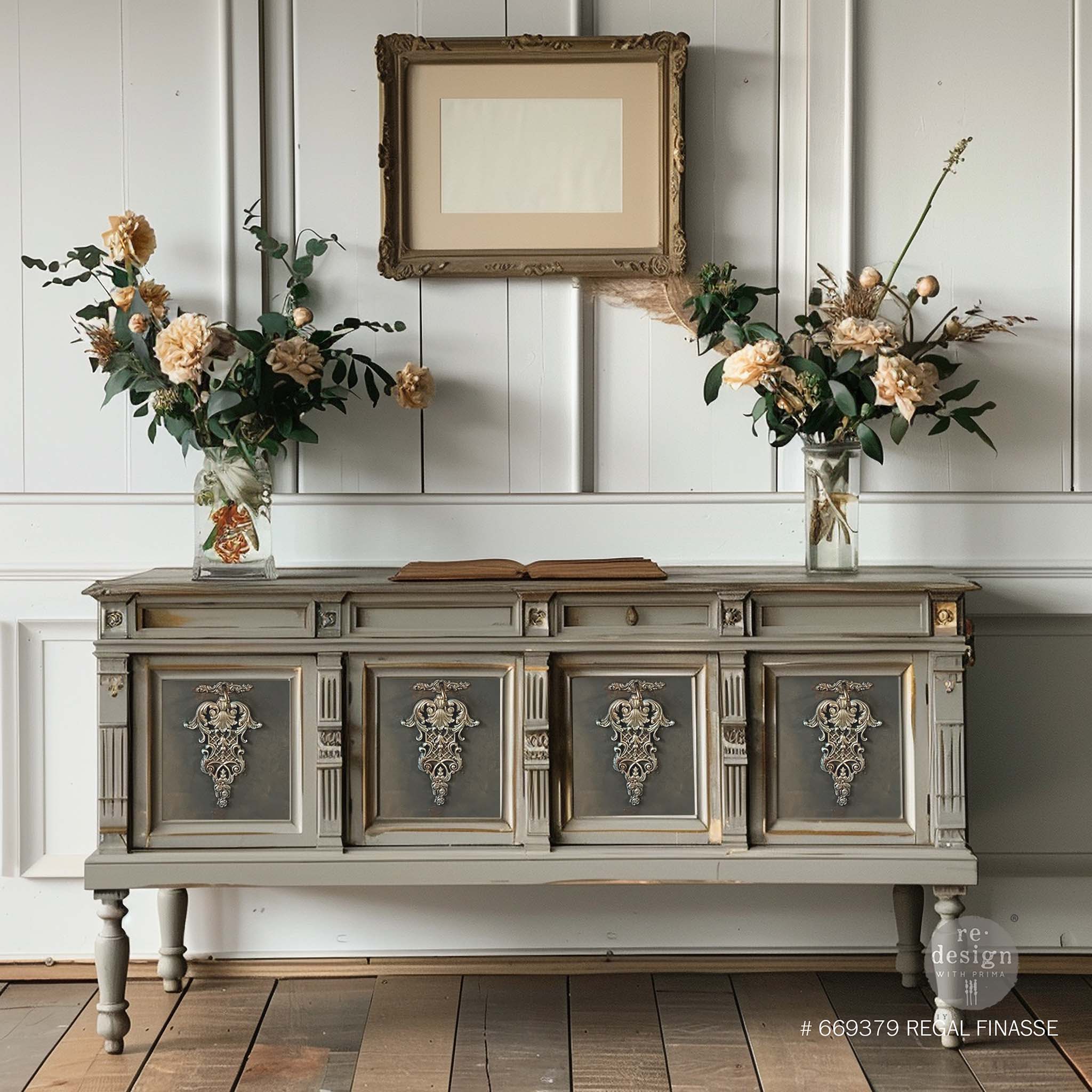 A vintage console table with 4 doors is painted different shades of gray and features ReDesign with Prima's Regal Finasse Decor Poly Casting in the center of each door.