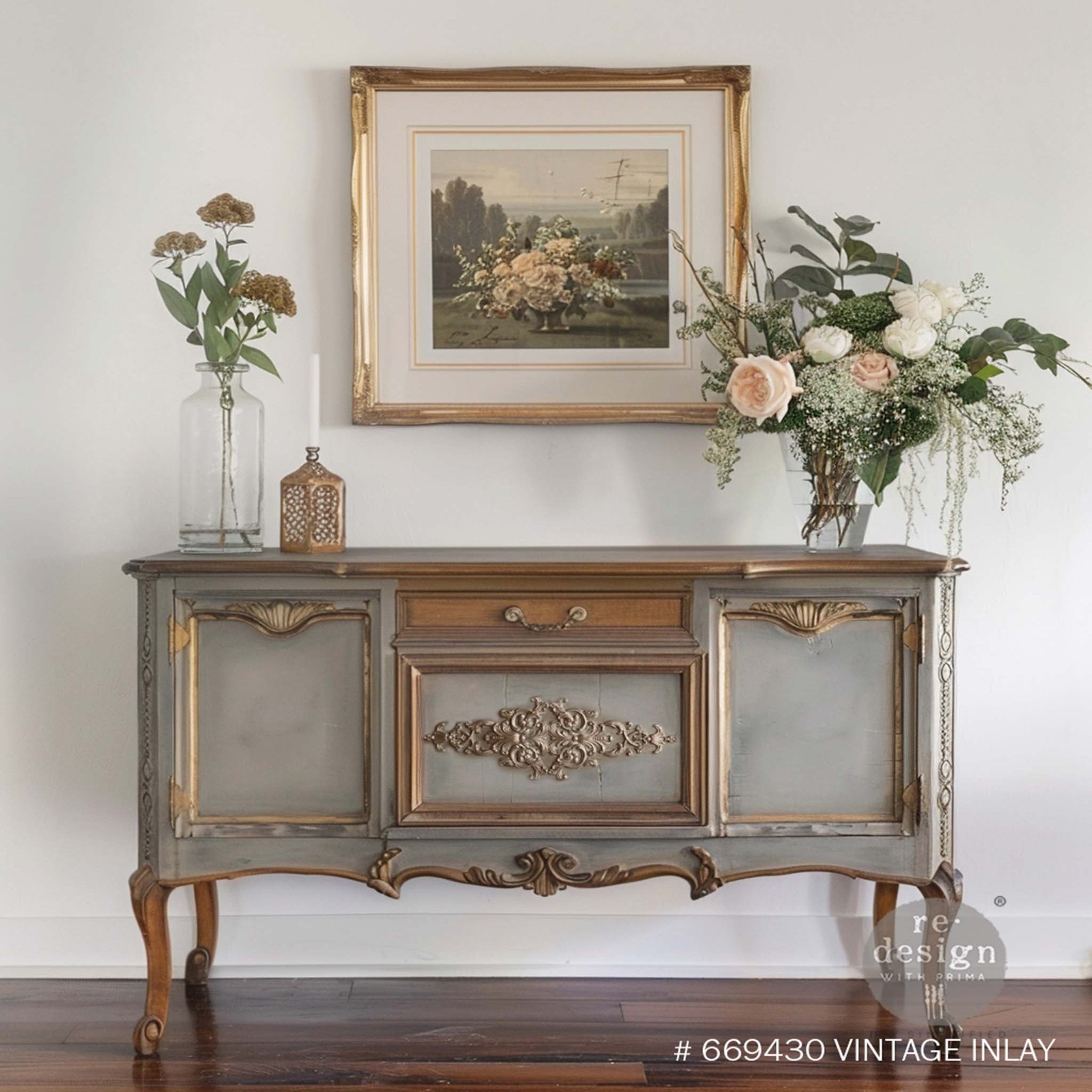 A vintage console table is painted gray with bronze accents and features ReDesign with Prima's Vintage Inlay Decor Poly on a center panel.