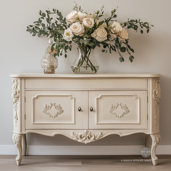 A vintage buffet cabinet is painted cream and features ReDesign with Prima's Intricate Grace Decor Poly Casting on its 2 doors.