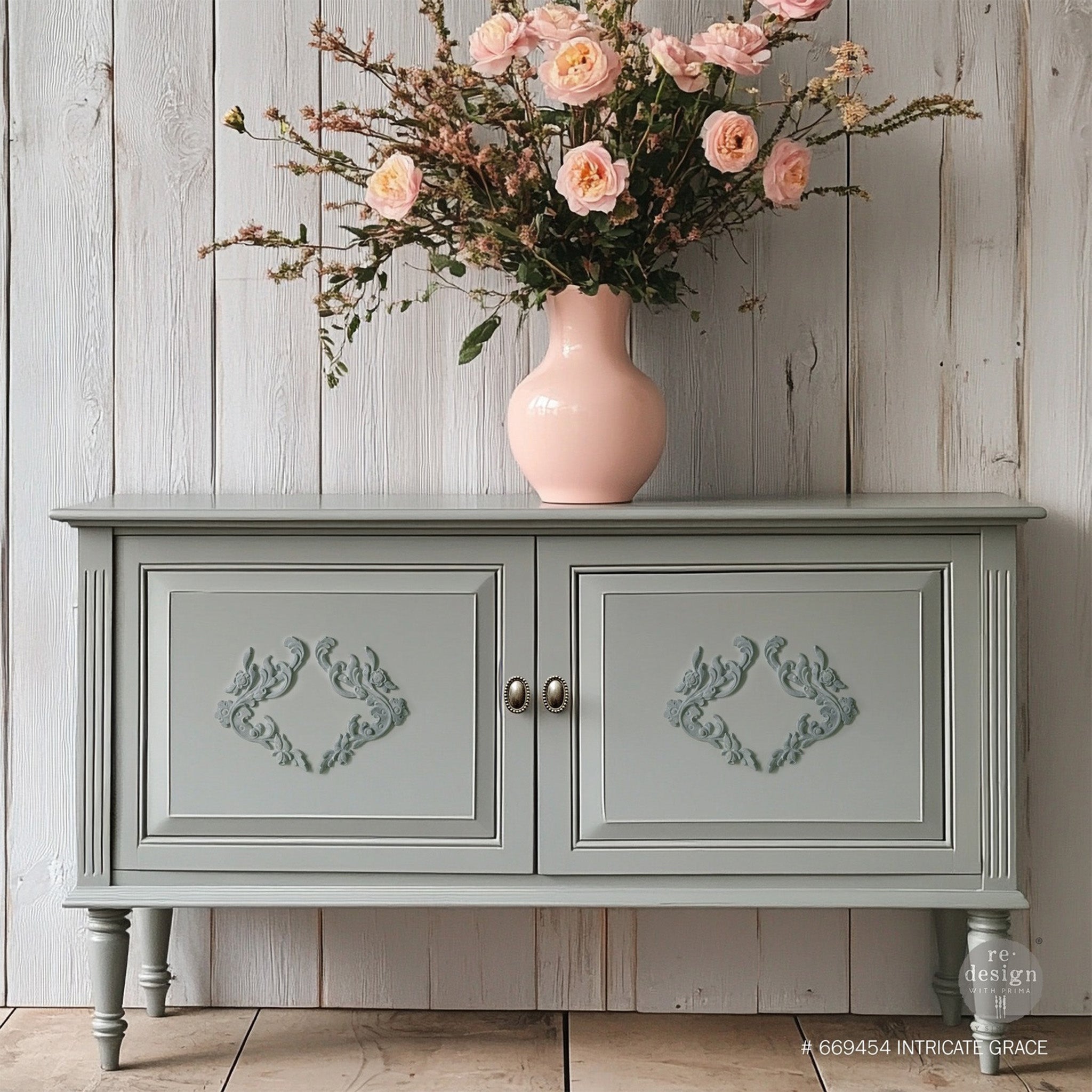 A console table with storage is painted light grey and features Redesign with Prima's Intricate Grace Decor Poly furniture applique in medium gray on the 2 doors.