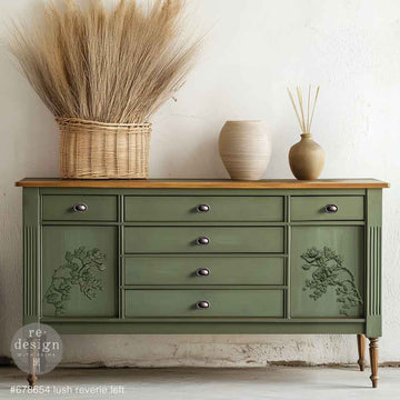 A large dresser with 6-drawers and 2 cabinet spaces is painted sage green with a natural wood top and feature ReDesign with Prima's Lush Reverie Left and Right Decor Poly castings on the cabinet doors.