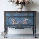 A vintage dresser is painted distressed blue and features ReDesign with Prima's Velvet Cascade Left and Right Decor Poly castings in silver on the front.
