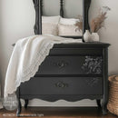 A vintage 2-drawer dresser with an attached mirror is painted charcoal black and features ReDesign with Prima's Velvet Cascade Right Decor Poly casting on the right side of its 2 drawers.