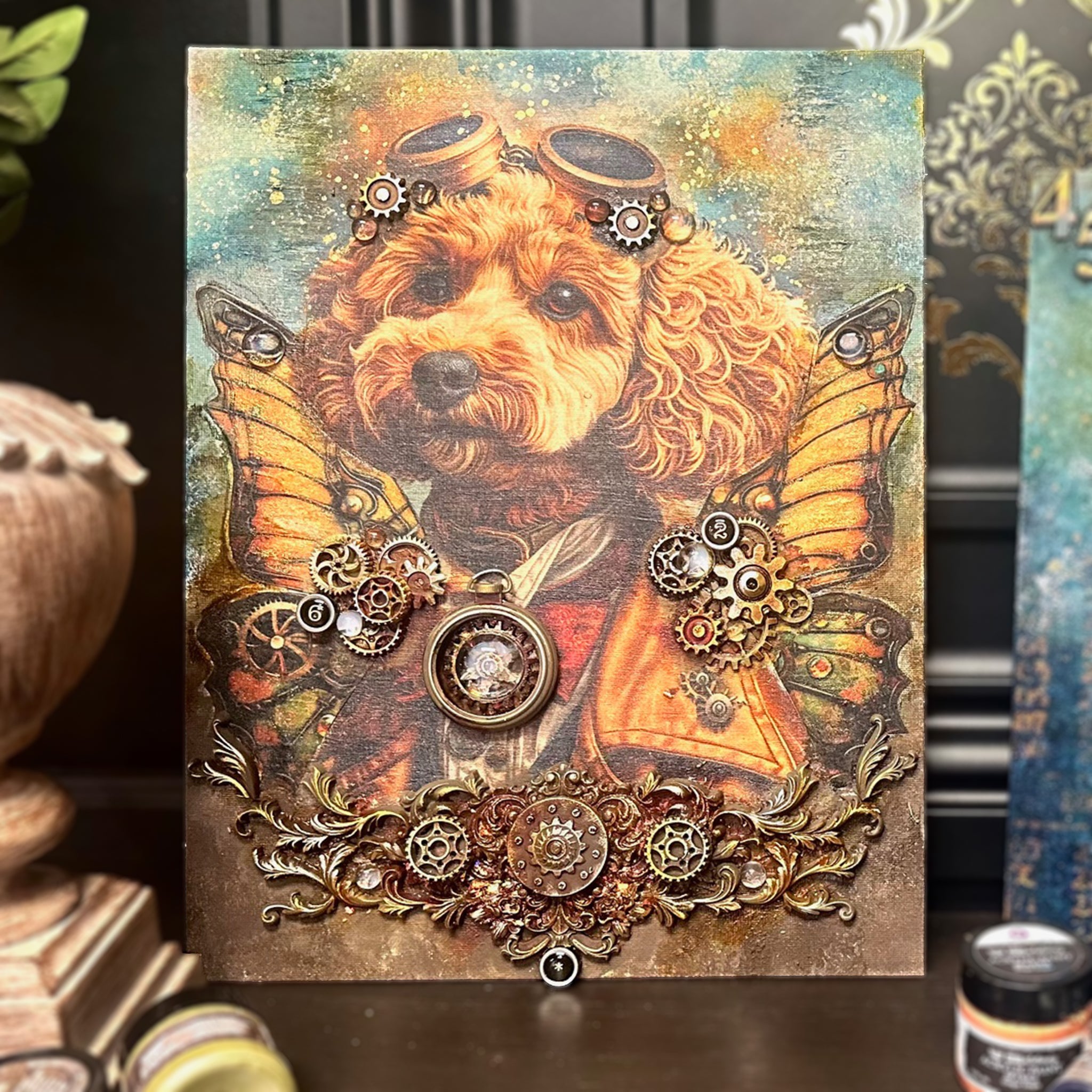 A canvas with 3d mold castings and gold cogs and gears features the small size puppy design from ReDesign with Prima's Favorite Pets fiber decoupage paper.