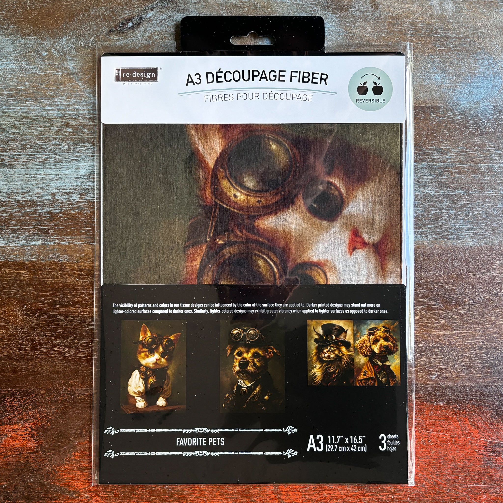 A package of ReDesign with Prima's Favorite Pets exclusive fiber paper 3 pack is against a dark wood background.