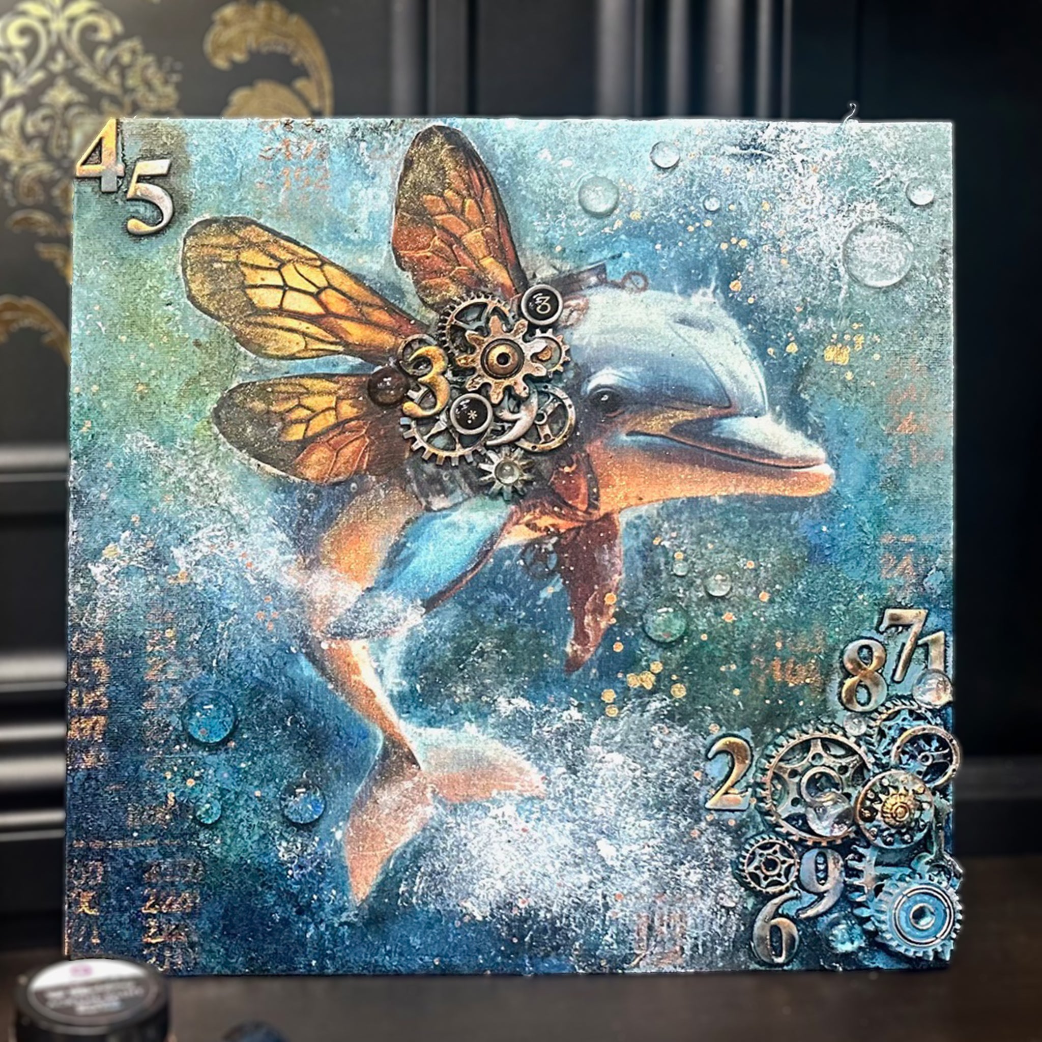 A canvas with 3d mold castings and cogs and gears features the dolphin from ReDesign with Prima's Royal Blues fiber decoupage paper.