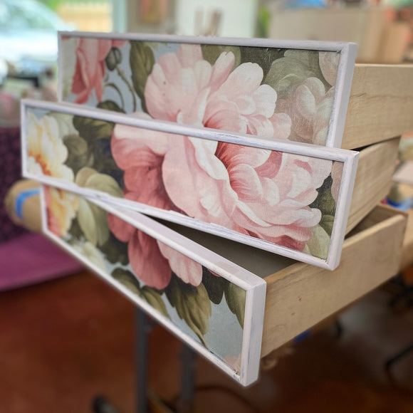 Three drawers are stacked on each other and are painted white featuring ReDesign with Prima's Salone de la Gloire A1 fiber paper on the drawer inlays.