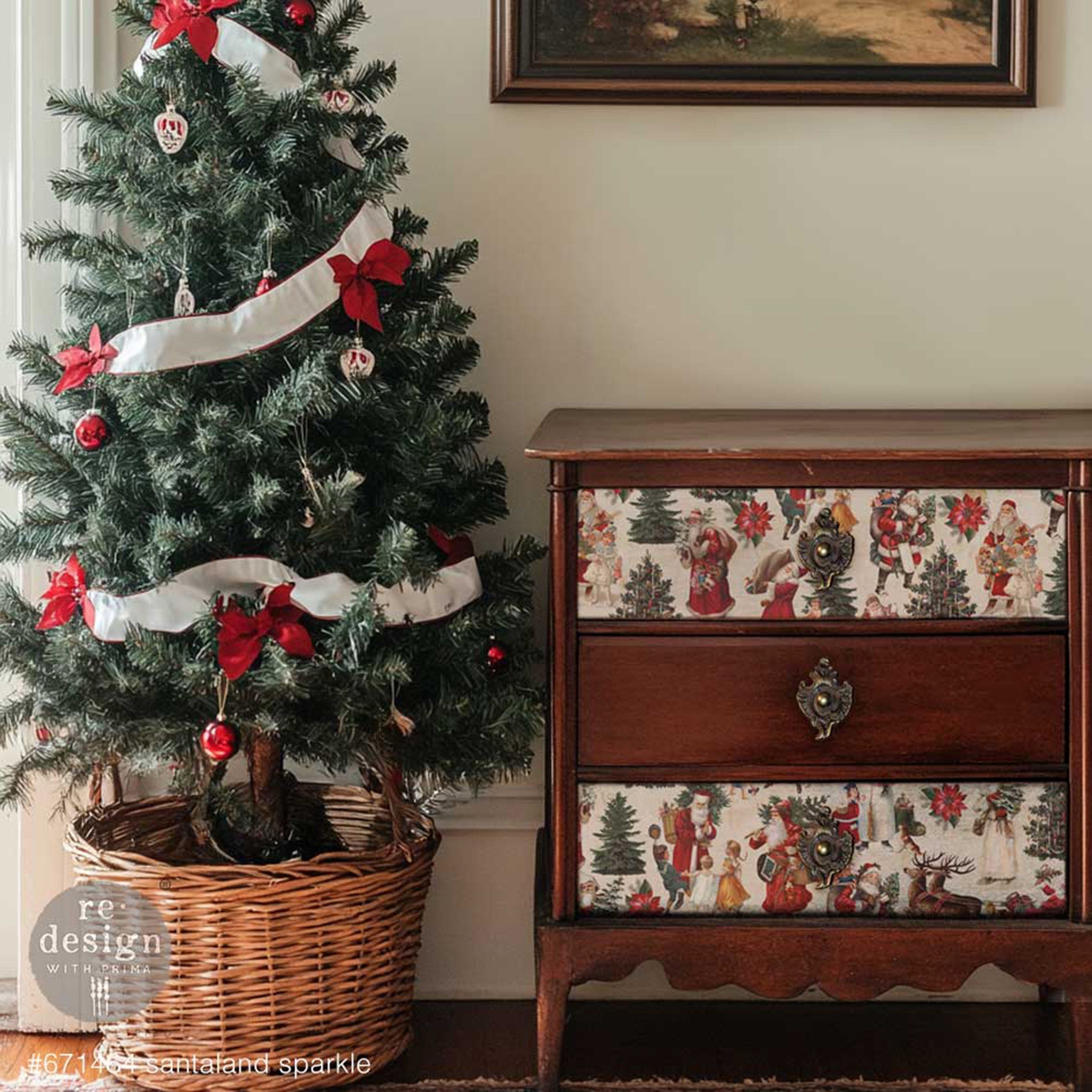 A vintage 3-drawer nightstand has dark natural wood and features ReDesign with Prima's Santaland Sparkle A3 fiber paper on the top and bottom drawer. A Christmas tree is to the left of the nightstand.