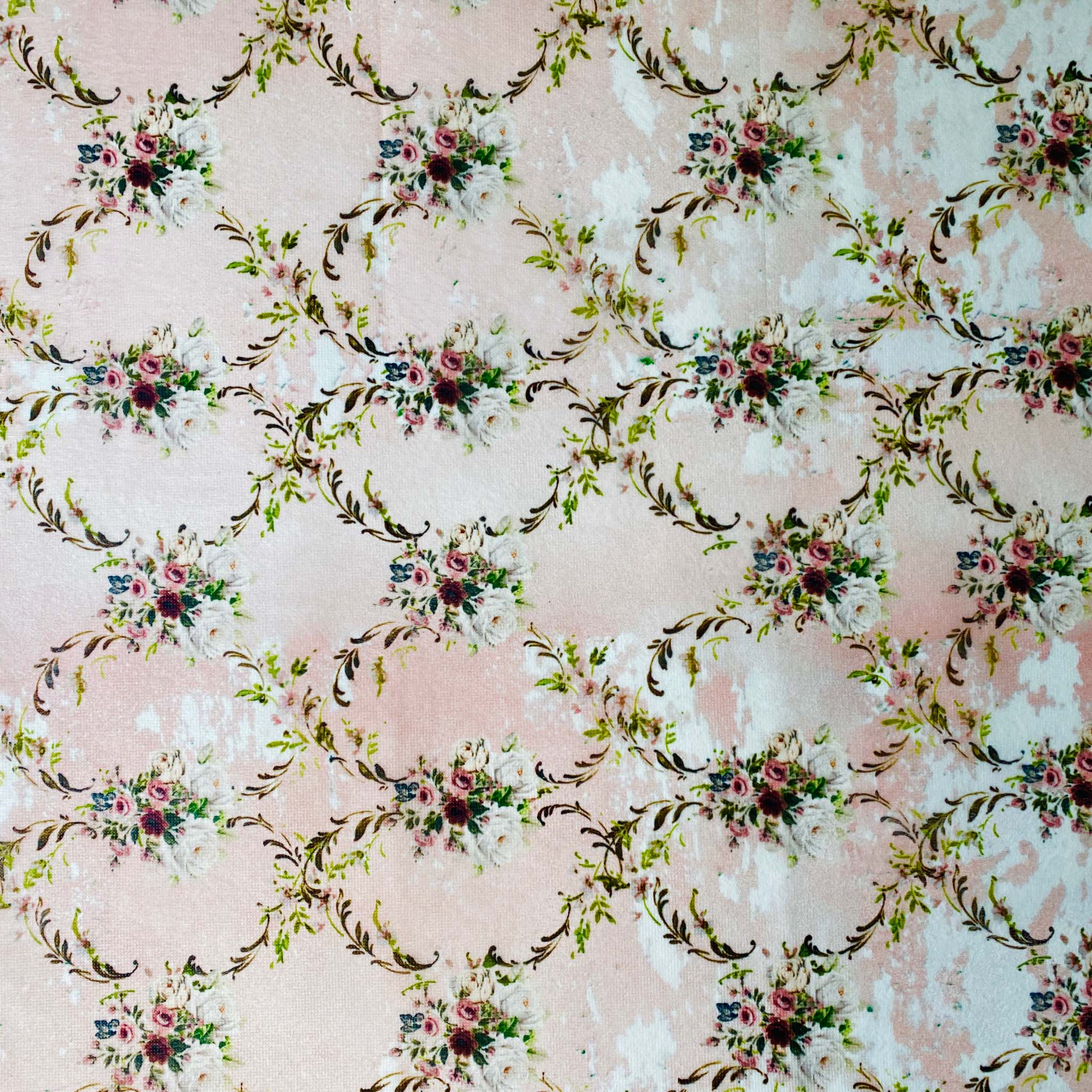 A close-up of a tissue paper design that features a repeating dainty floral diamond vining design against a pale pink and white background.