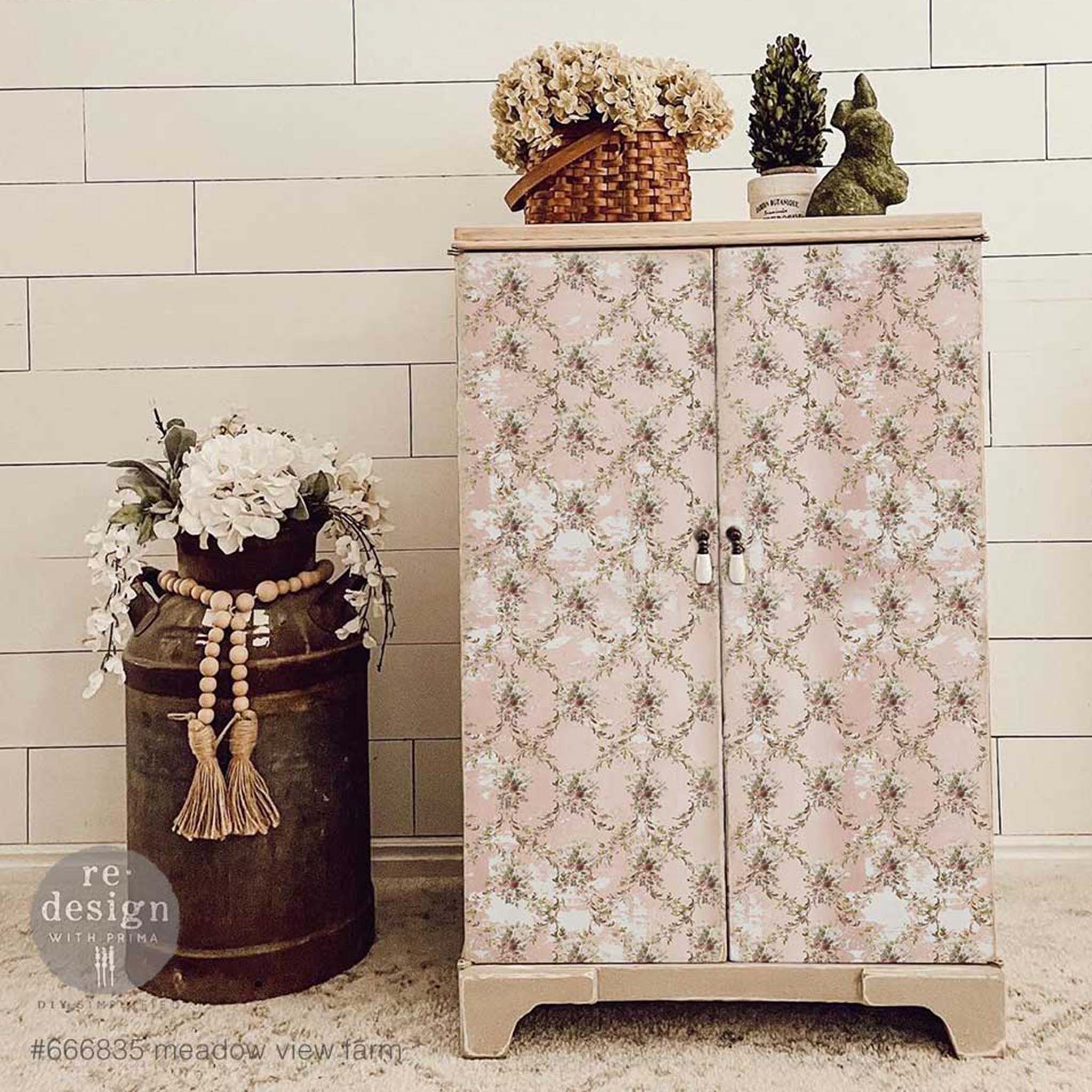 A vintage bathroom storage cabinet is natural wood and features ReDesign with Prima's Meadow View Farm tissue paper on its 2 doors.