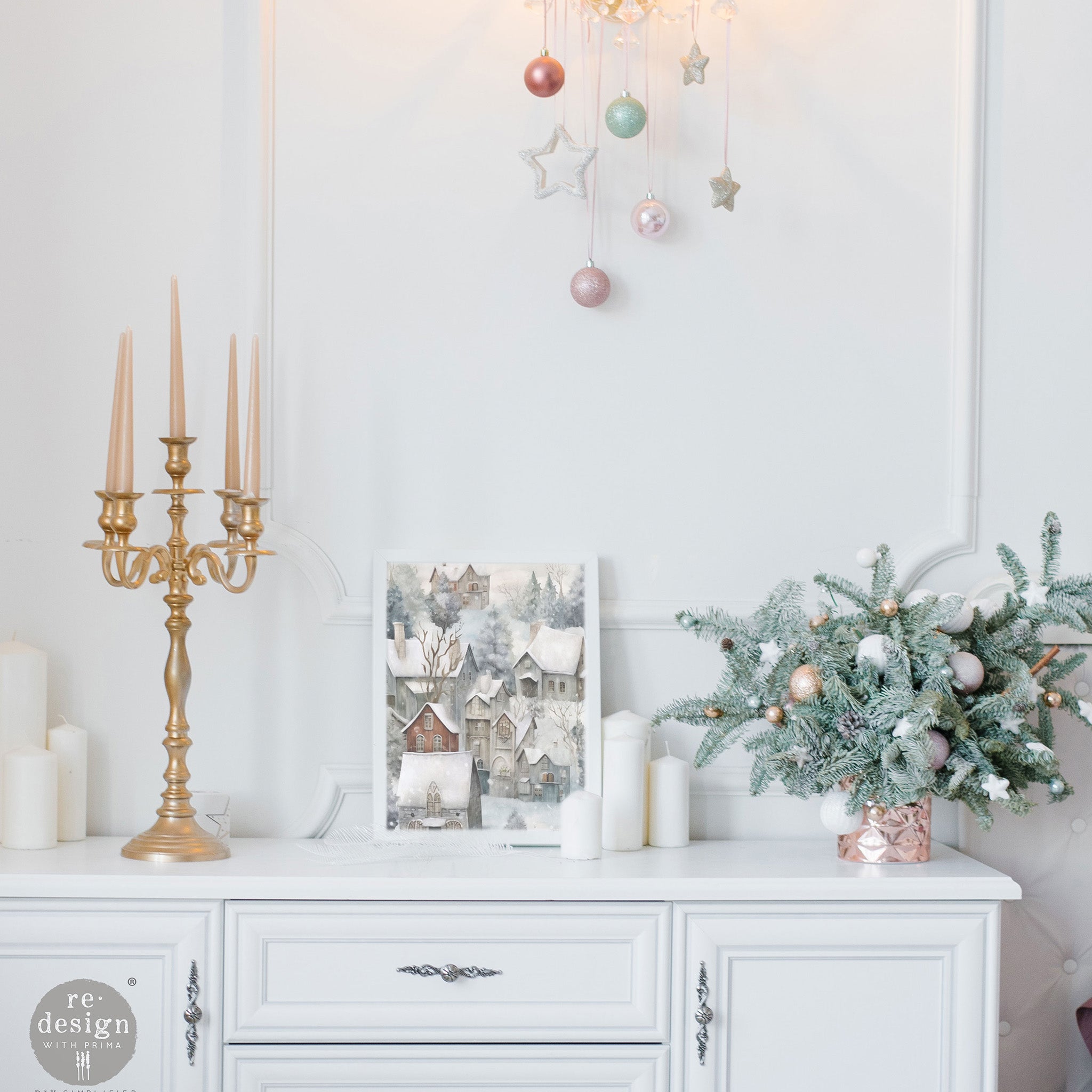 A white buffet table features a white picture frame with ReDesign with Prima's Silent Night Snow Village fiber paper in it.