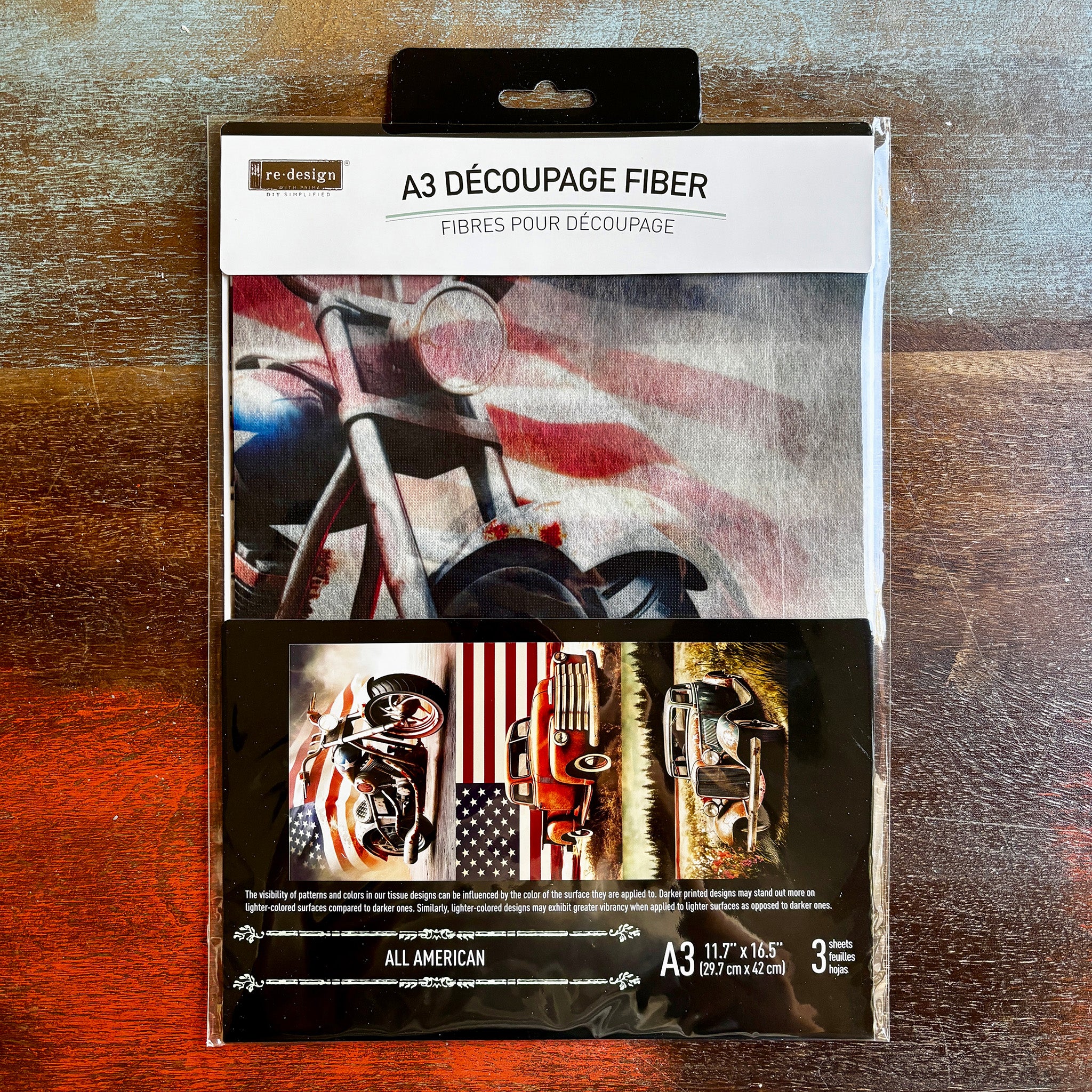 A package of ReDesign with Prima's All American fiber paper is against a dark wood background.