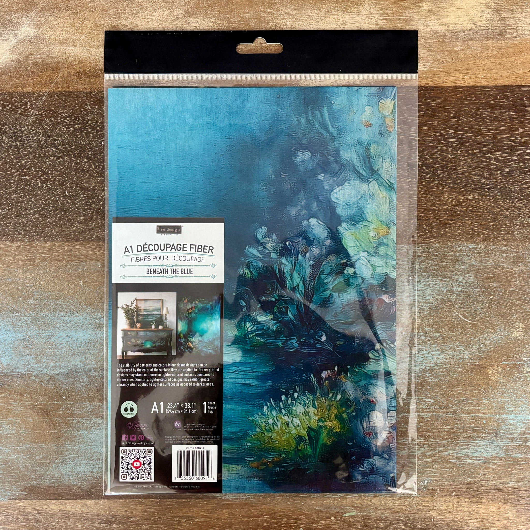 A package of ReDesign with Prima's Beneath the Blue Exclusive Fiber Paper Bundle is against a wood background.