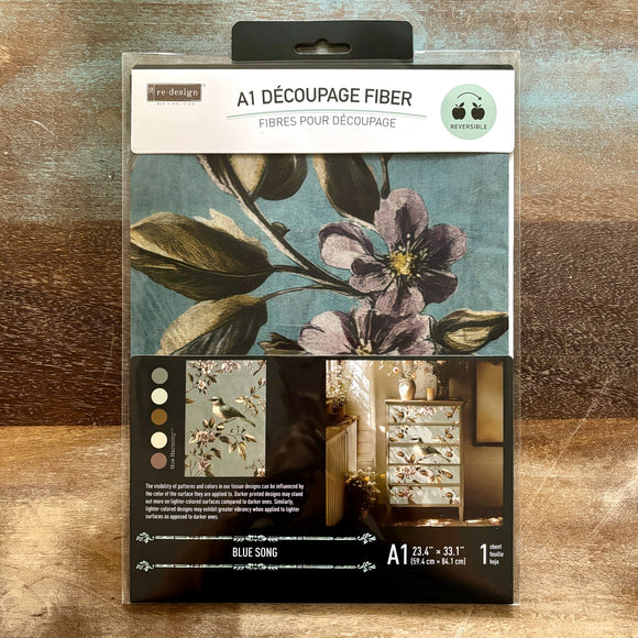 A package of ReDesign with Prima's Blue Song A1 fiber paper is against a wood background.