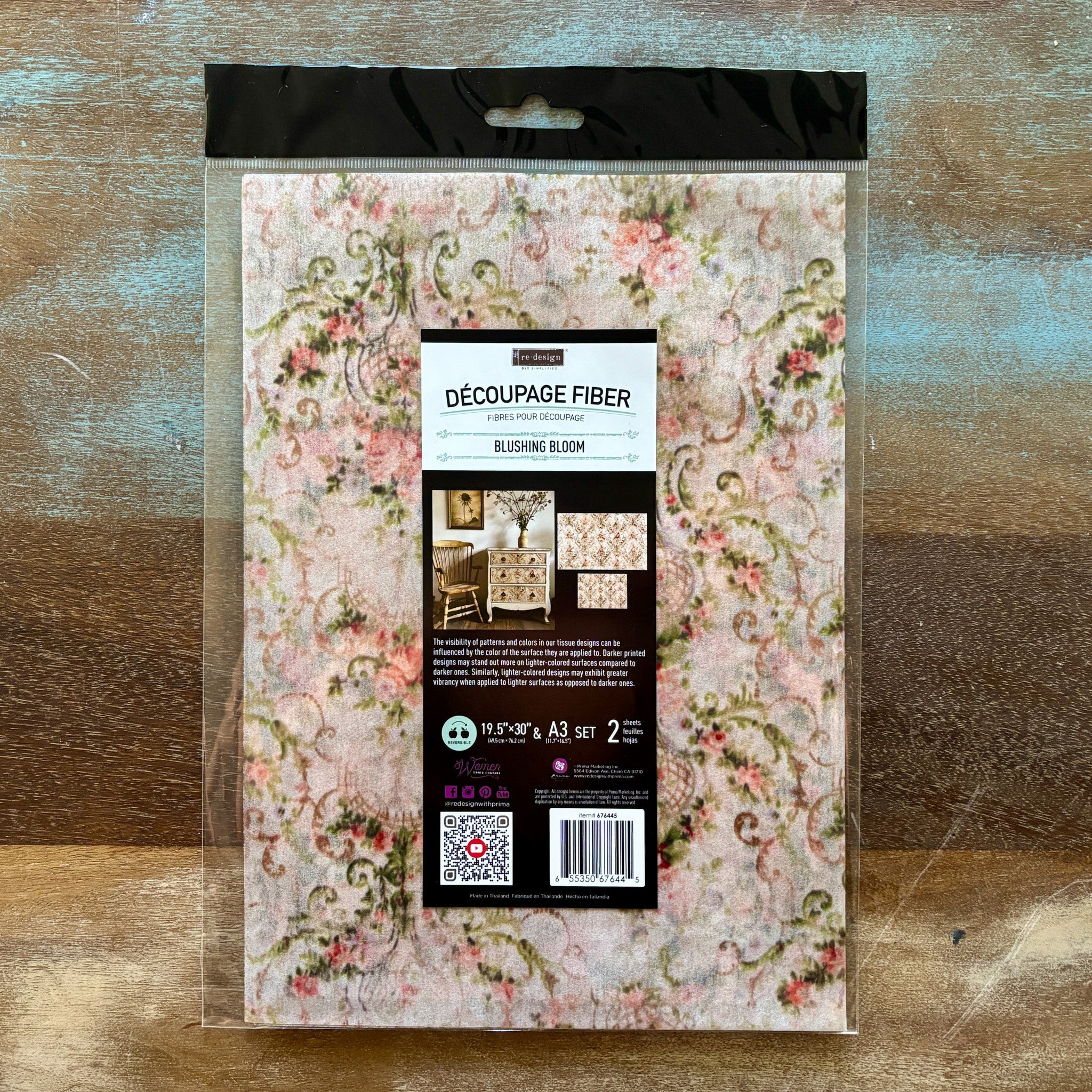 A package of ReDesign with Prima's Blushing Bloom Fiber Paper is against a wood background.
