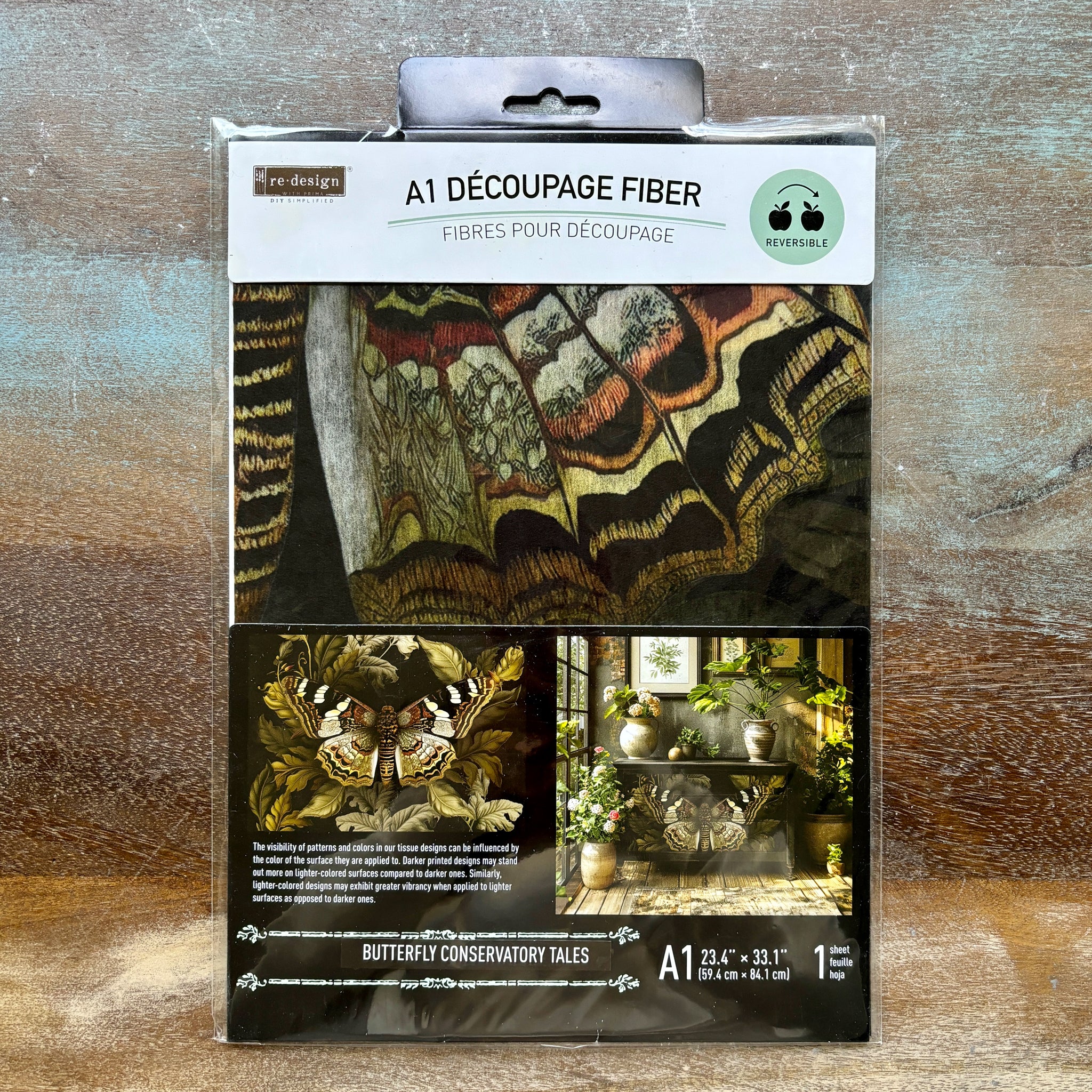 A package of ReDesign with Prima's Butterfly Conservatory Tales A1 fiber paper is against a wood background.