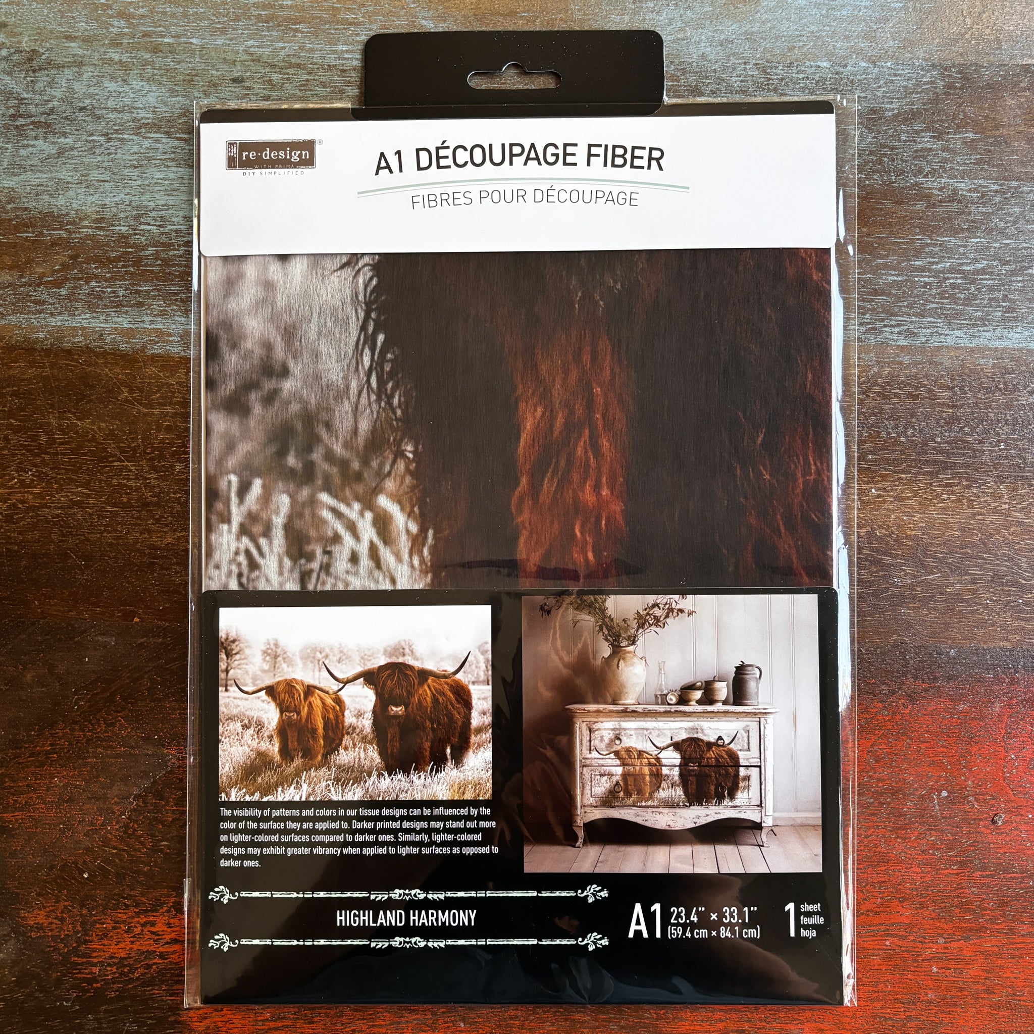 A package of ReDesign with Prima's Highland Harmony fiber paper is against a dark wood background.