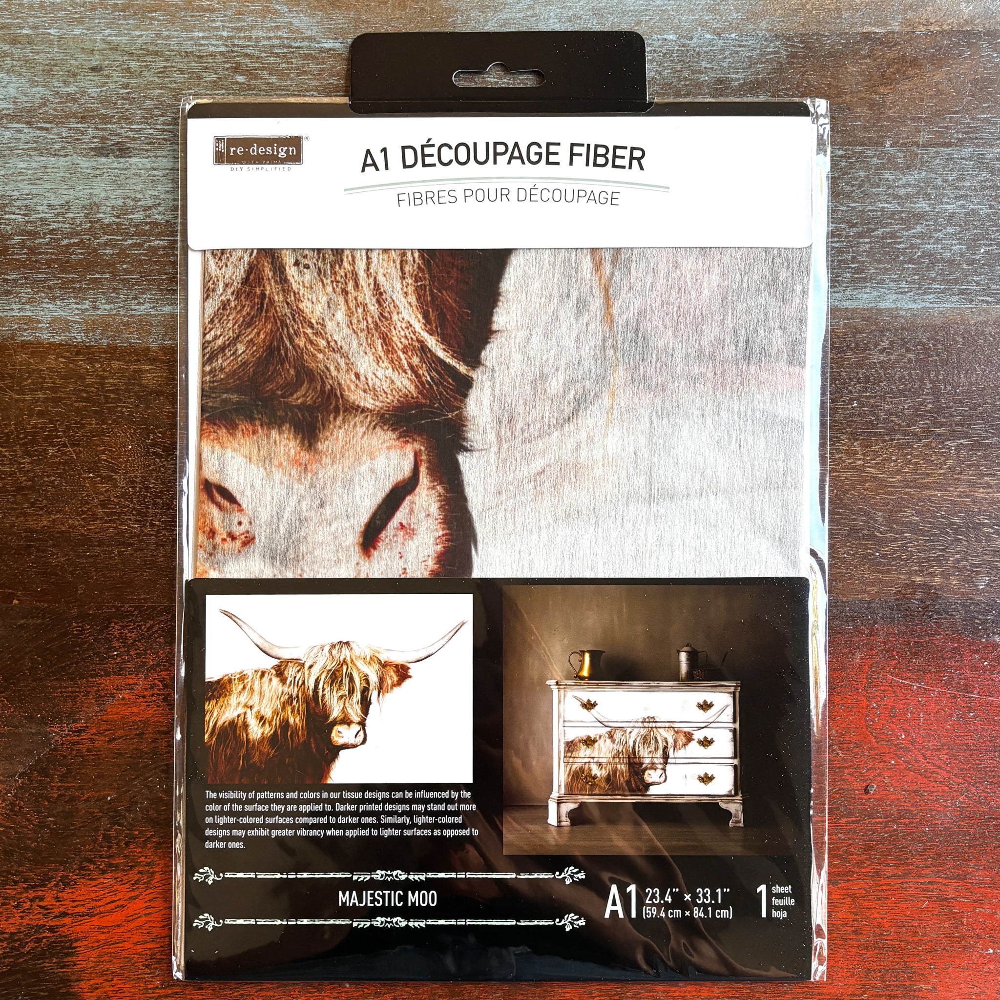 A package of ReDesign with Prima's Majestic Moo fiber paper is against a dark wood background.