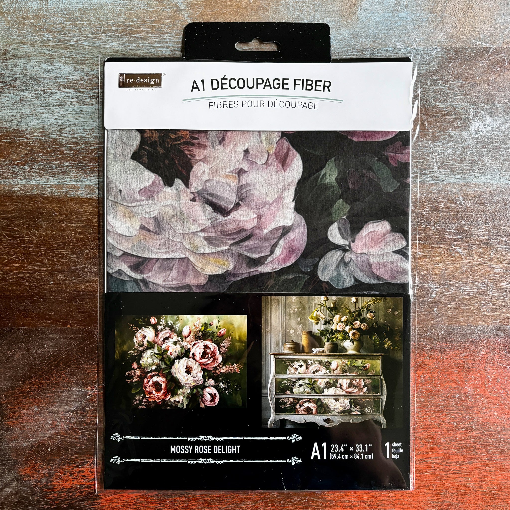 A package of ReDesign with Prima's Mossy Rose Delight A1 fiber paper is against a dark wood background.