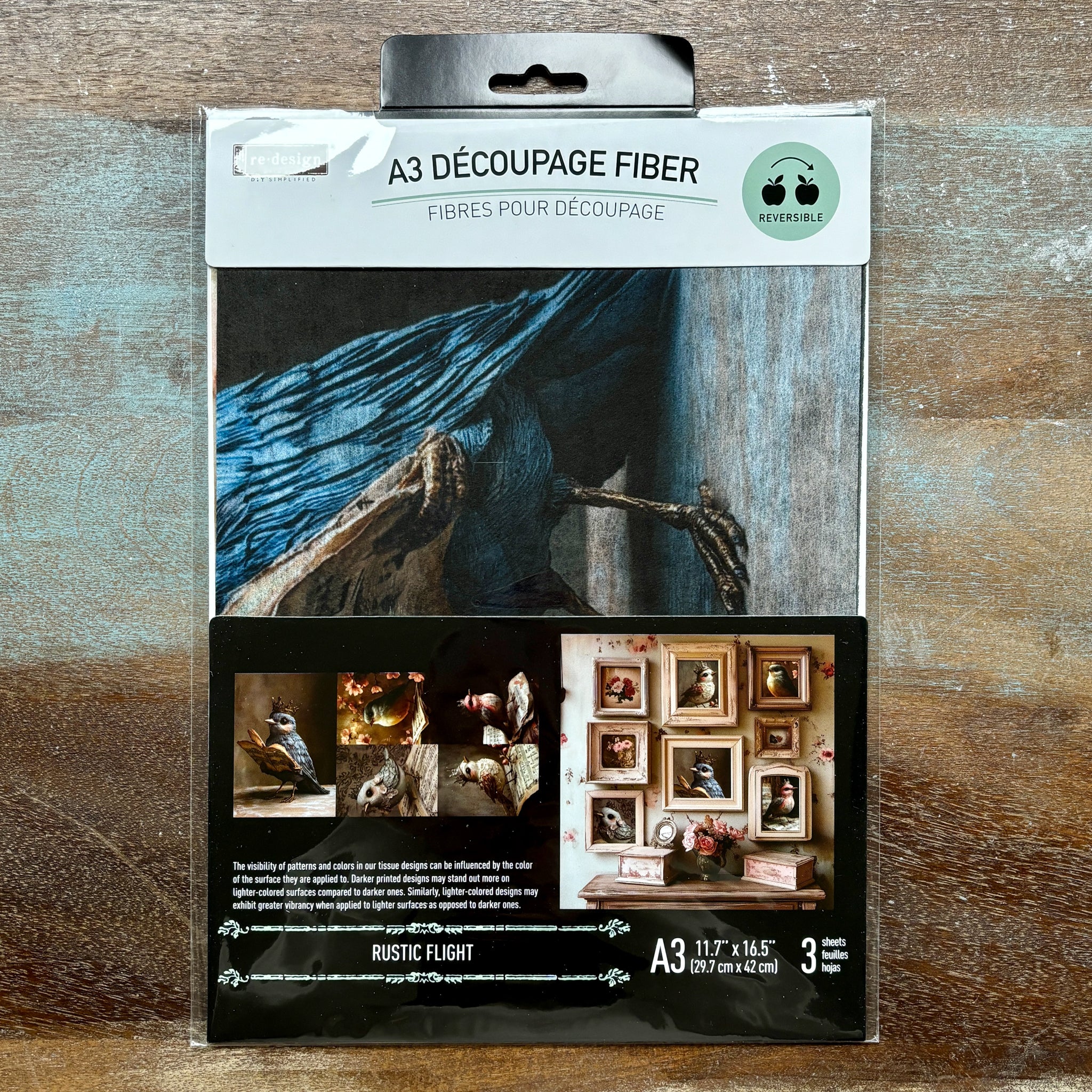 A package of ReDesign with Prima's Rustic Flight A3 fiber paper 3 pack is against a wood background.