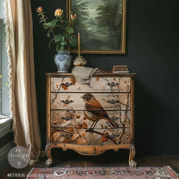 Decorative chest of drawers with bird and floral design in a room with dark walls and a window.
