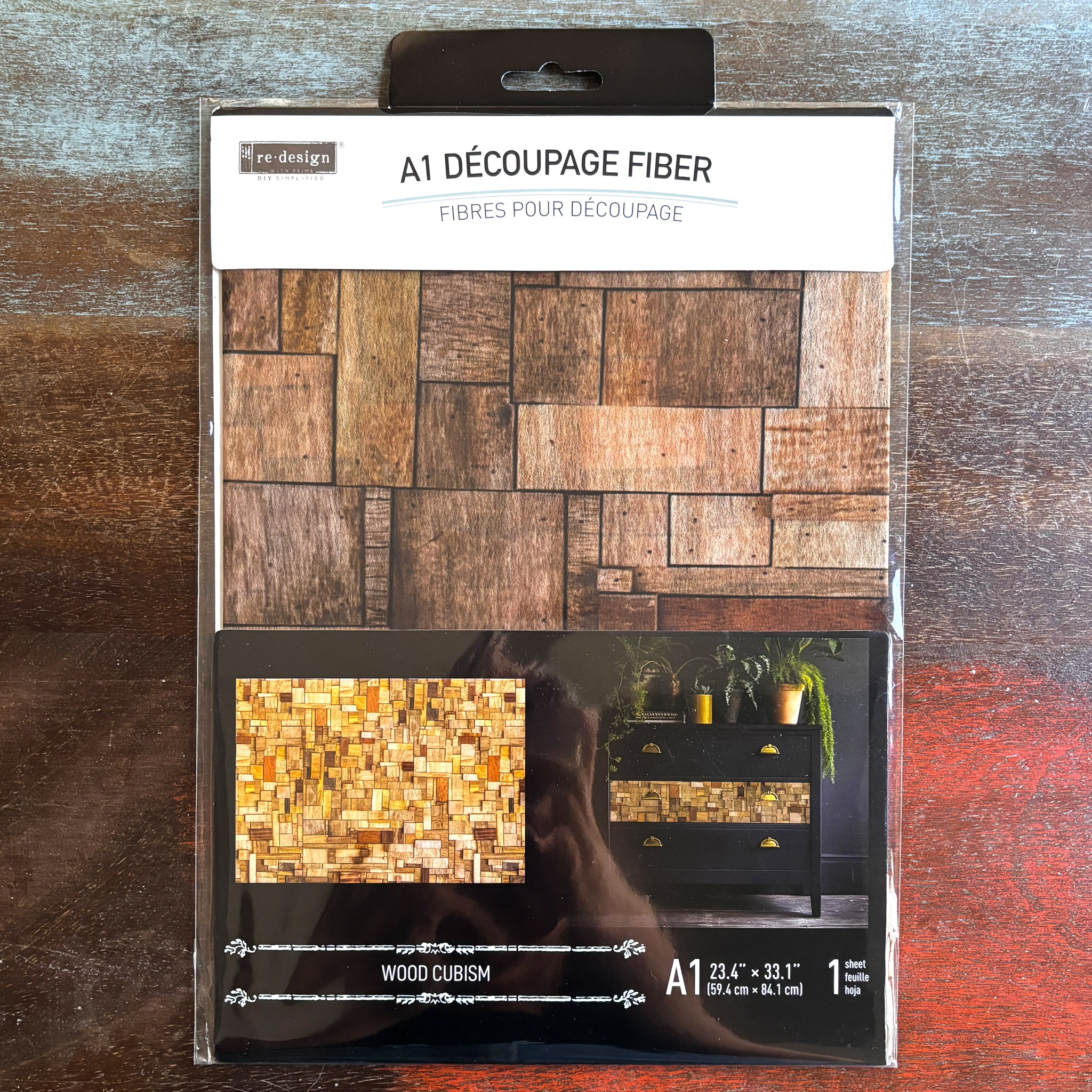 A package of ReDesign with Prima's Wood Cubism fiber paper is against a dark wood background.