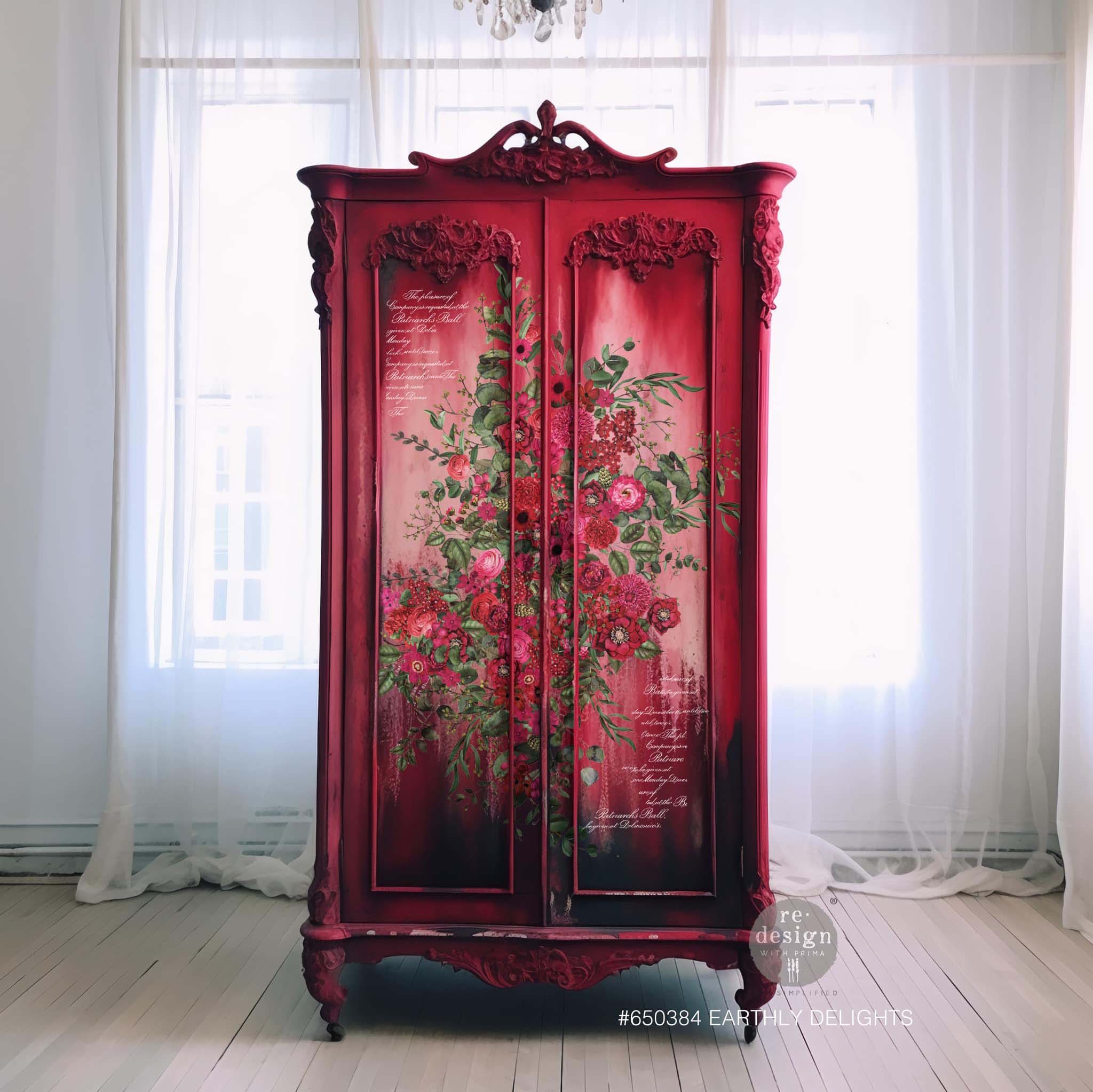 A vintage armoire is painted a blend of dark red, white in the center, and a soft blend of black near the bottom and features ReDesign with Prima's Earthly Delights rub on transfer in the center.