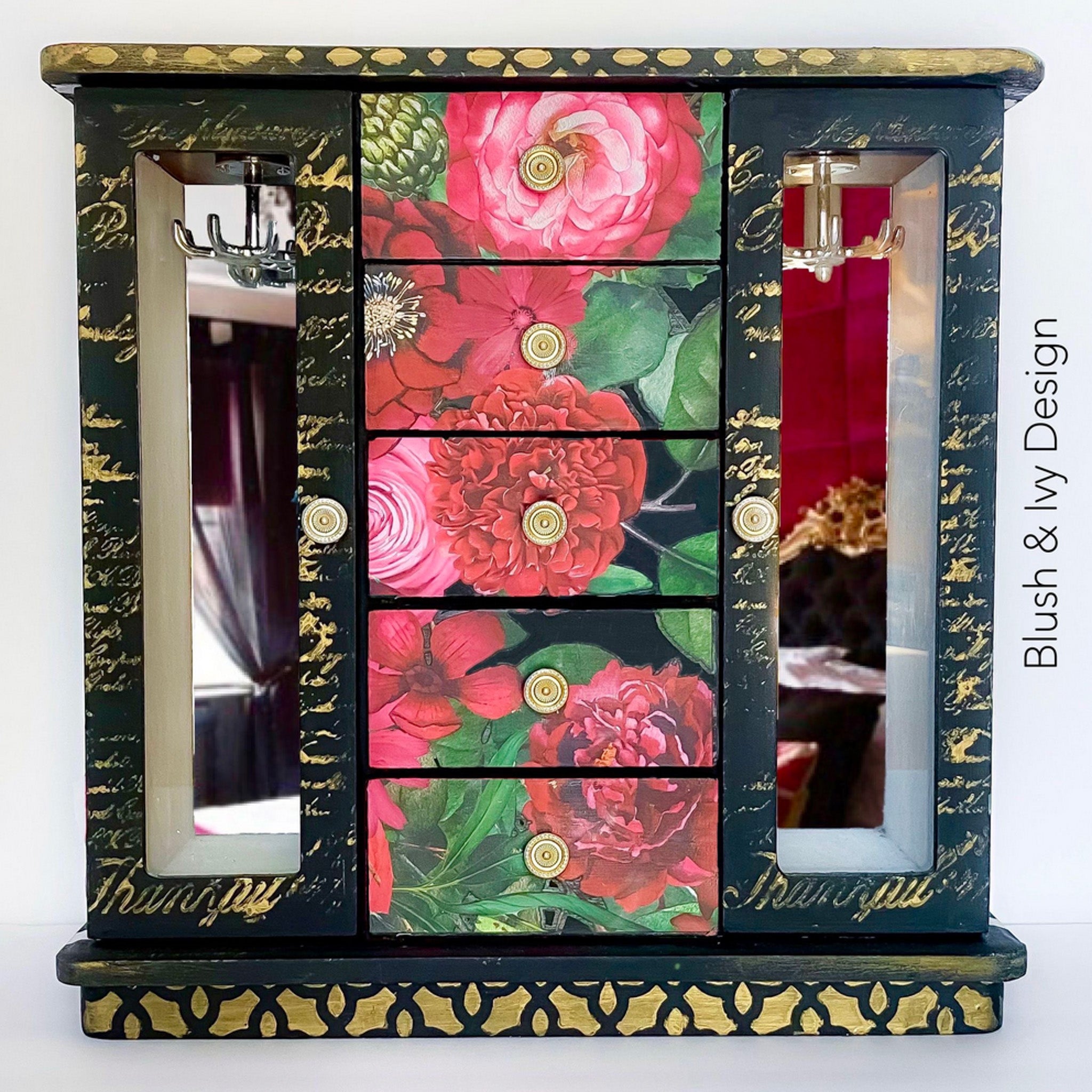 A table top jewelry armoire refurbished by Blush and Ivy Design is painted black with white stripes on the sides and features ReDesign with Prima's Earthly Delights rub on transfer on it.