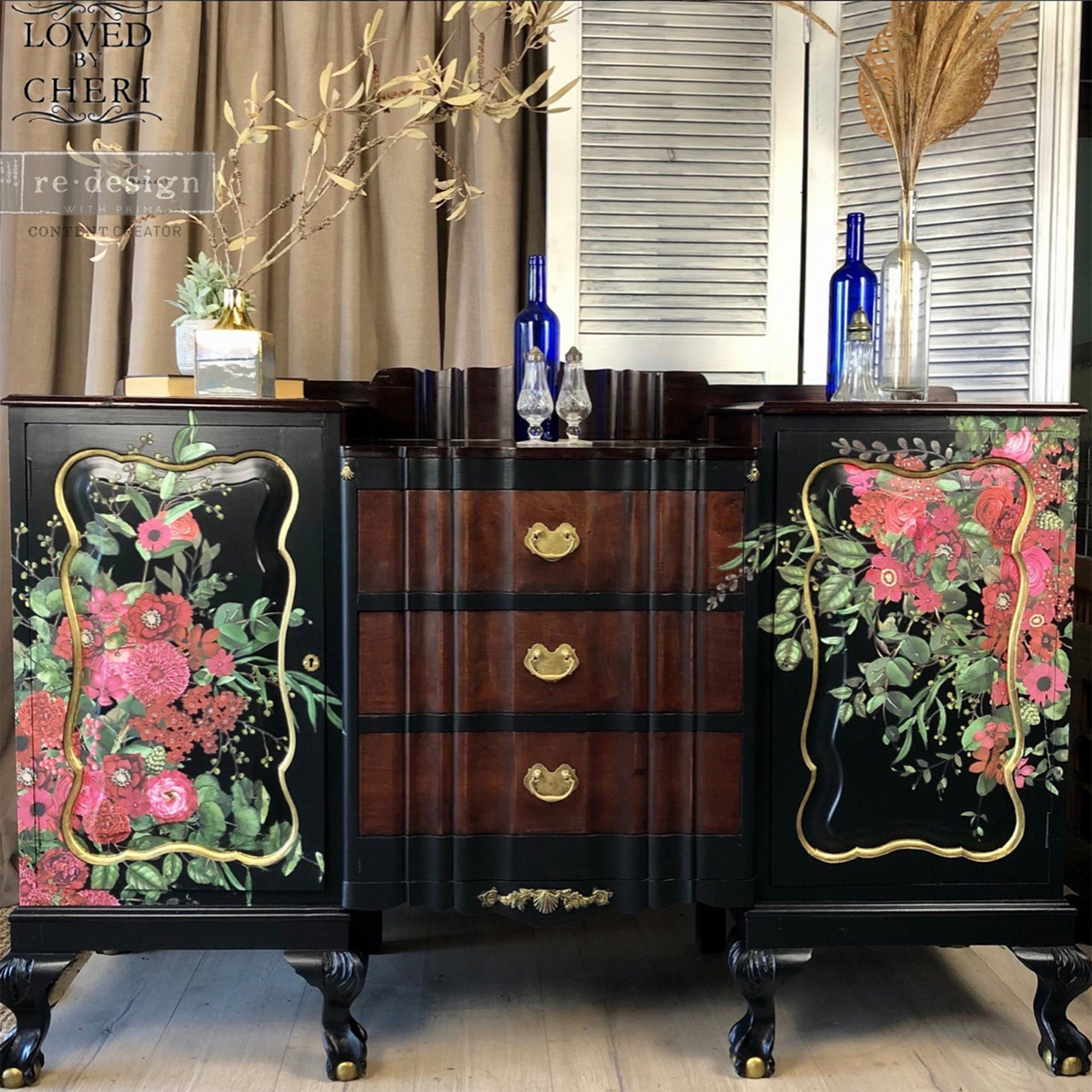 A vintage large buffet console refurbished by Loved by Cheri is painted black with 3 natural wood drawers in the center and features ReDesign with Prima's Earthly Delights rub on transfer on its 2 doors on either side of the drawers.