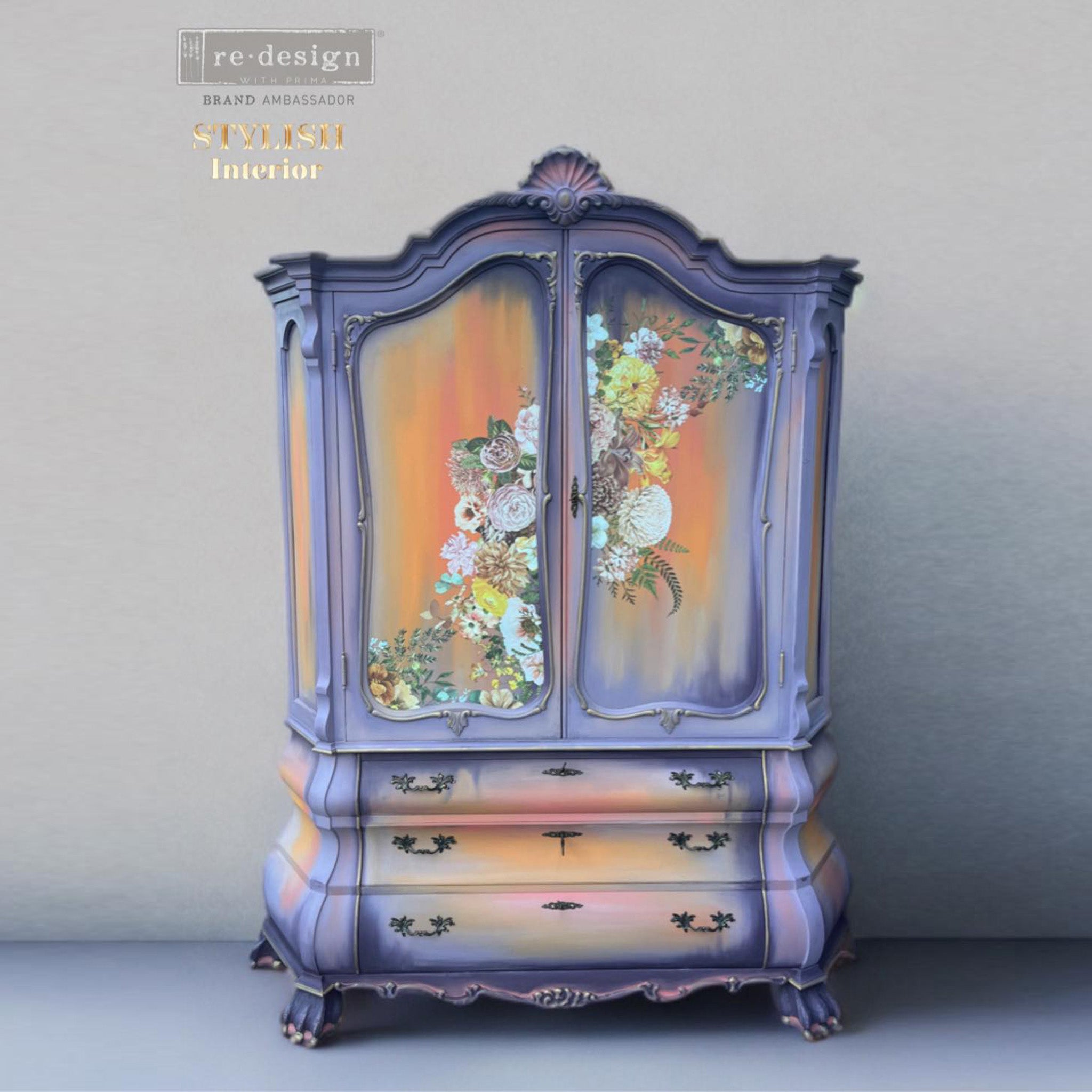 A vintage armoire refurbished by Stylish Interior is painted lavender with soft orange ombre in the center of its doors, drawers, and sides, and features ReDesign with Prima's Kacha Elegant Neutrals rub-on transfer on the doors.