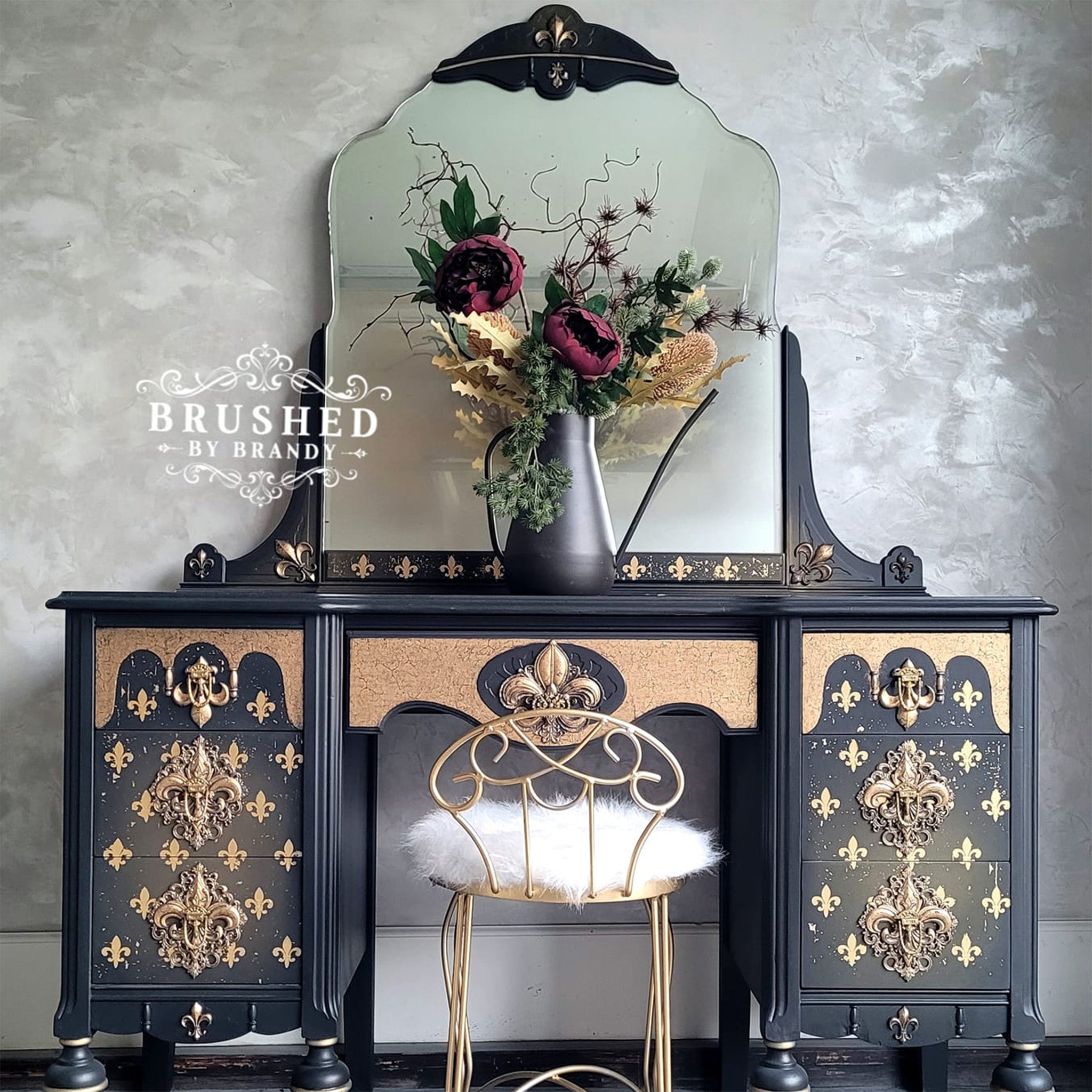 A vintage vanity desk refurbished by rushed by Brandy is painted dark navy blue with gold accents and features Redesign with Prima's Fleur de Lis Gold transfer on it.