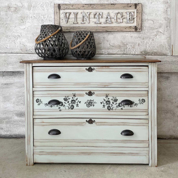 A vintage 3-drawer dresser is painted white and features the Blossomy H2O trasnfer on its center drawer.