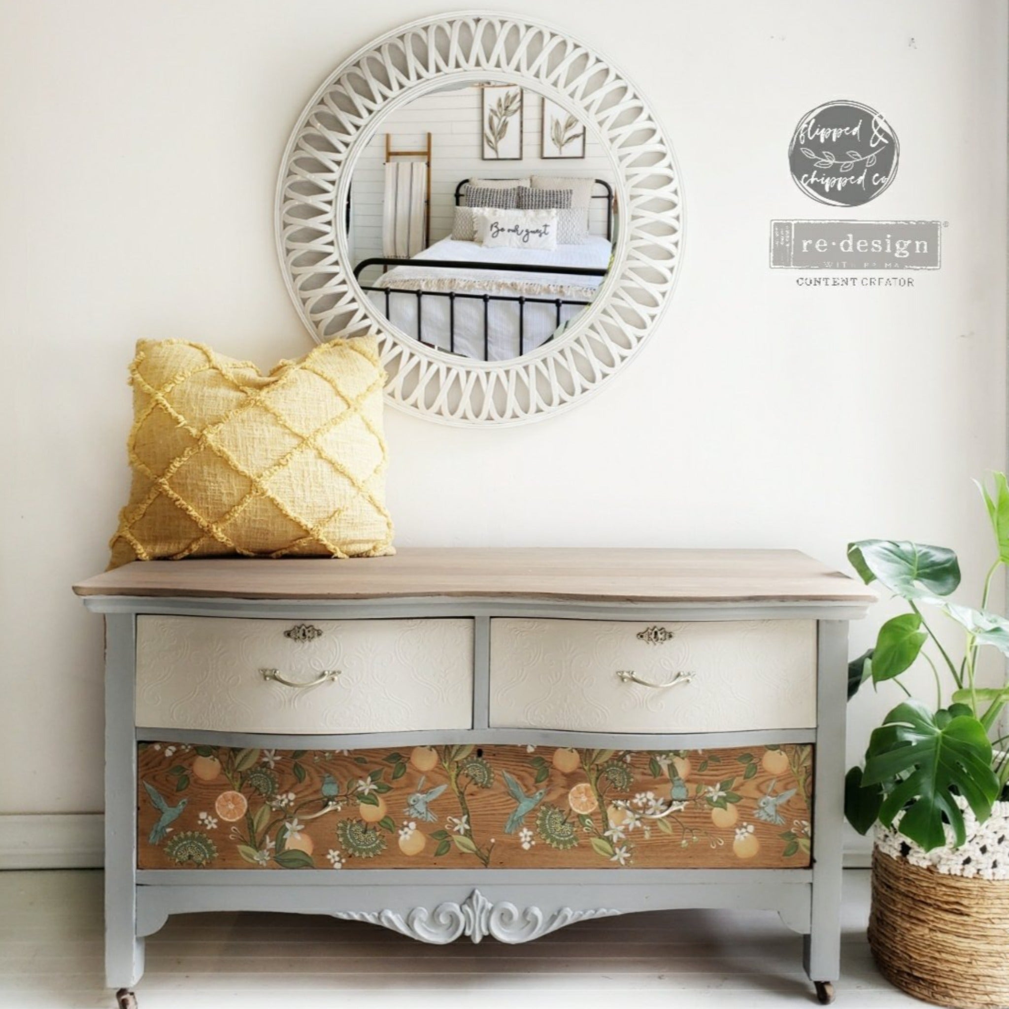 A 3-drawer dresser refurbished by Flipped & Chipped Company is painted light grey with 2 white drawers and a large natural wood drawer. ReDesign with Prima's Orange Grove transfer is featured on the natural wood drawer.