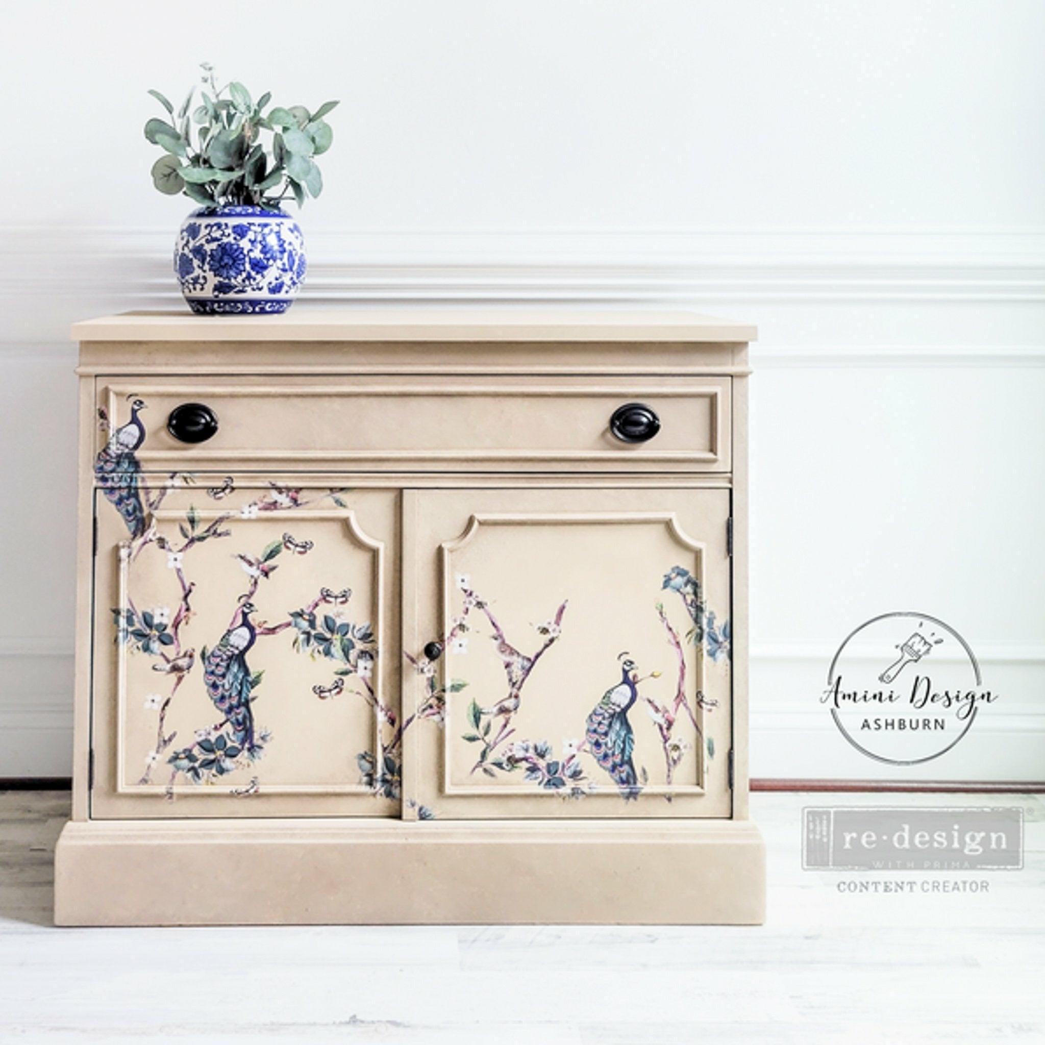 A small buffet cabinet refurbished by Amini Design Ashburn is painted beige and features ReDesign with Prima's Avian Sanctuary rub on transfer on the front.