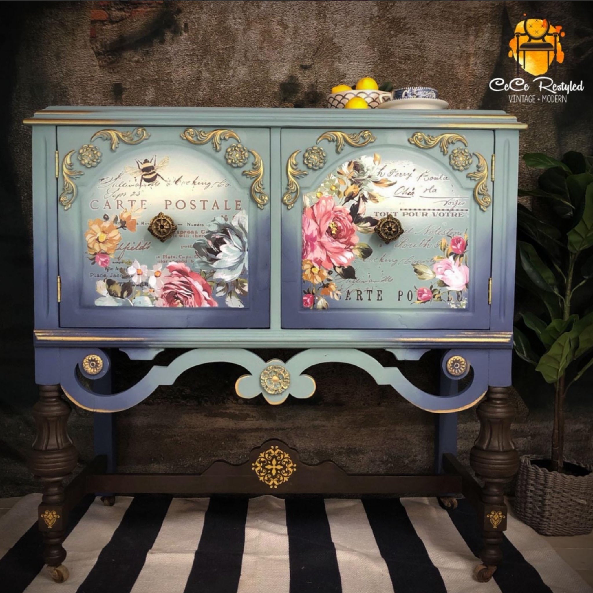 A vintage console table with storage refurbished by CeCe ReStyled is painted a blend of light blues and features ReDesign with Prima's Fuchsia Sunset rub on transfer on the 2 door inlays.