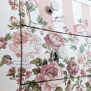 Close-up of Blushing Blooms Symphony rub-on transfer detail—soft blush and mauve roses with leafy vines applied over pink-and-white striped drawer front.