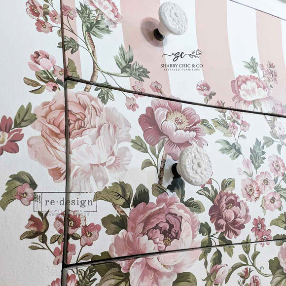 Close-up of Blushing Blooms Symphony rub-on transfer detail—soft blush and mauve roses with leafy vines applied over pink-and-white striped drawer front.