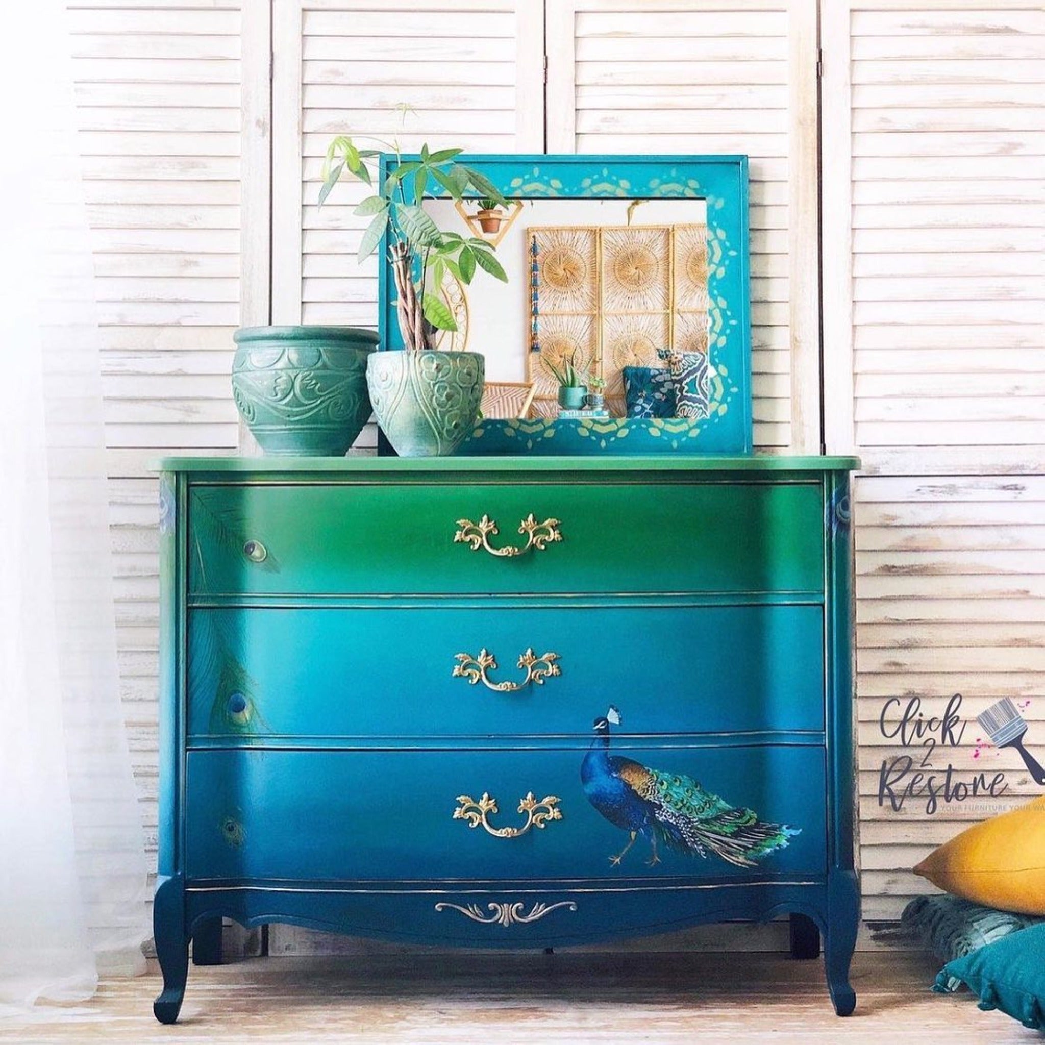 A vintage 4-drawer large dresser refurbished  by Click 2 Restore is painted an ombre blend of green down to blue and features a peacock from ReDesign with Prima's Peacock Dreams transfer on the bottom drawer.