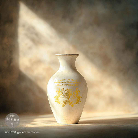 A white ceramic vase features ReDesign with Prima's Gilded Memories H2O Water Slide Transfer on it.