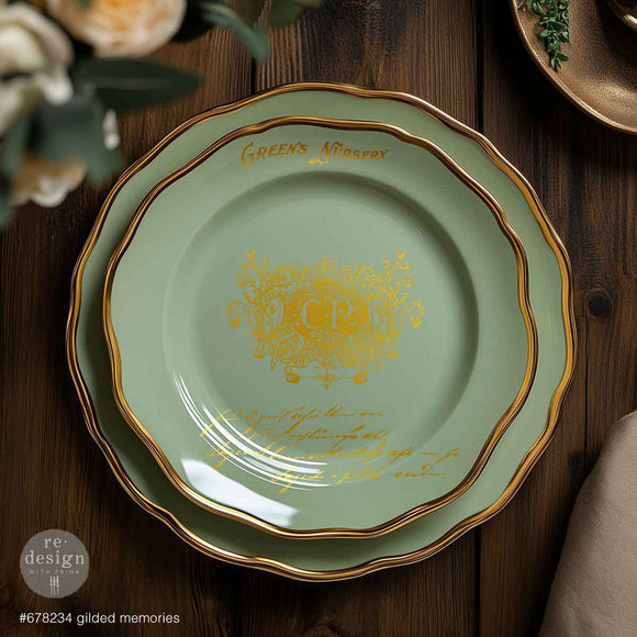 A large and small Tiffany blue colored plates with gold trim are on a decorated wood table. The small plate features ReDesign with Prima's Gilded Memories H2o Water Slide Transfers on it.