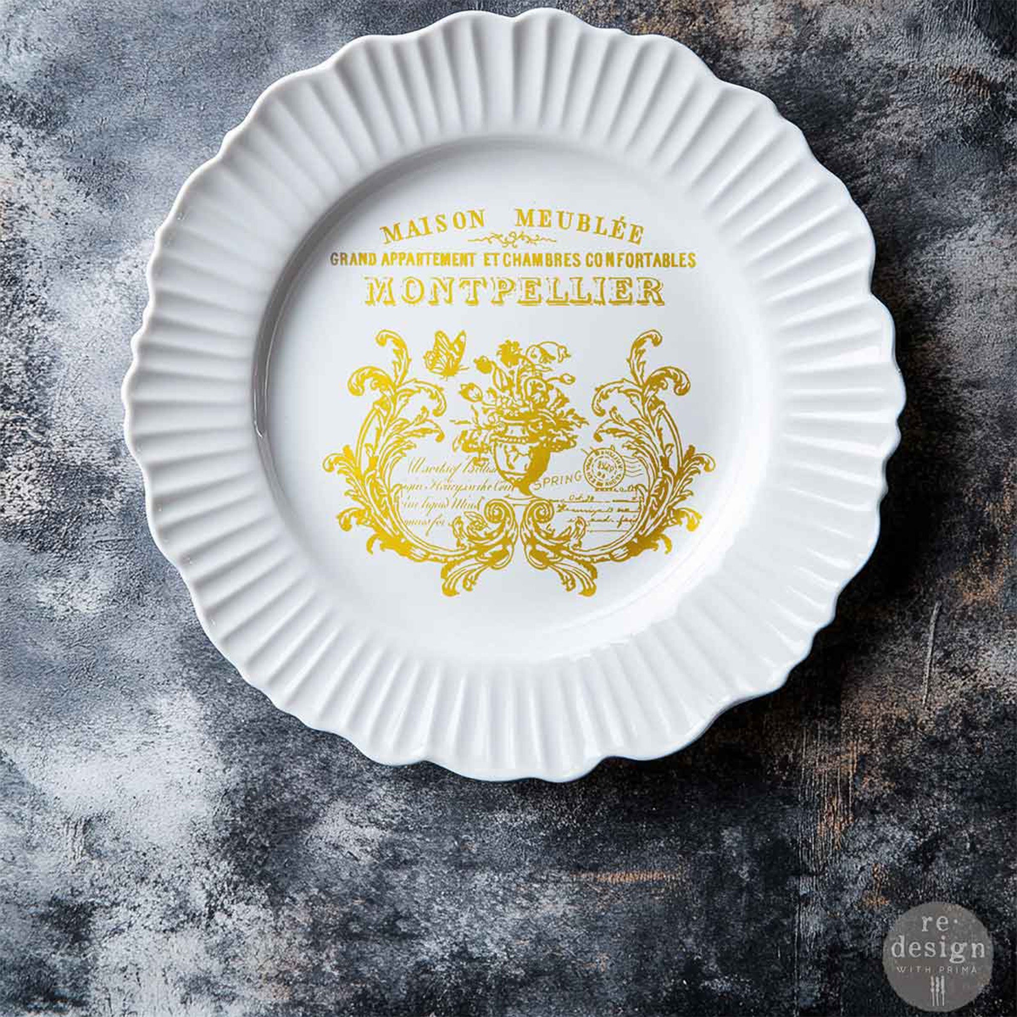 A scalloped edged white plate features ReDesign with Prima's Gilded Memories H2O Water Slide Transfer on it.