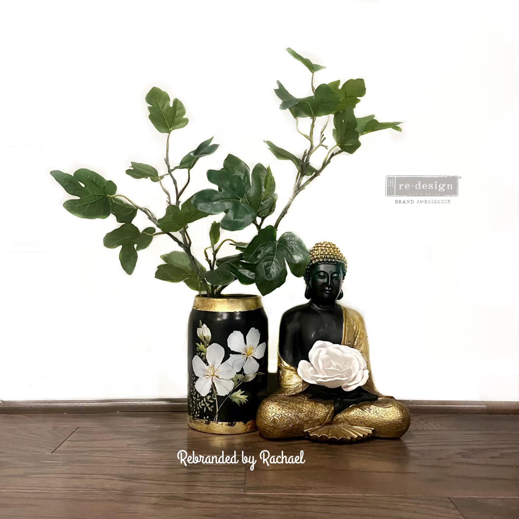 A black and gold colored vase refurbished by Rebranded by Rachael is next to a Buddah statue and features ReDesign with Prima's Froggy Meadow Greens 12" x 12" rub-on transfer.