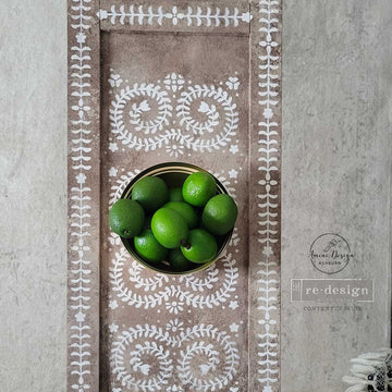 Narrow table runner board stenciled with Elegant Vine pattern with a bowl of limes on top