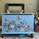 Decorative chest with bird and floral design on a green wall background