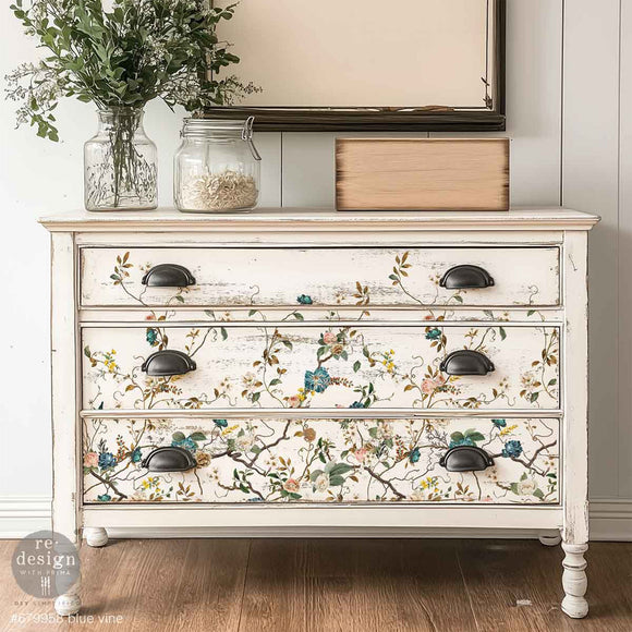 A vintage 3-drawer dresser is painted soft white and features ReDesign with Prima's Blue Vine rub-on furniture transfer on the drawers.