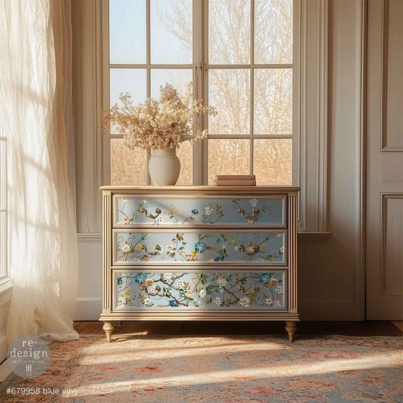 A 3-drawer dresser is painted light beige with pale blue drawer fronts and features ReDesign with Prima's Blue Vine rub-on transfer over the blue paint.