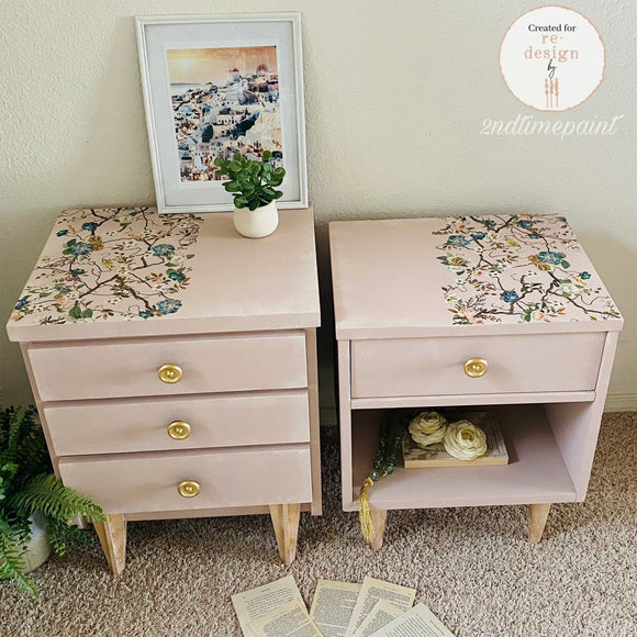 Pair of pink nightstands with floral decoupage on top, gold knobs, and books underneath.