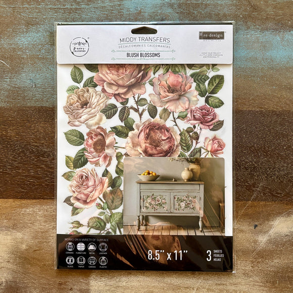 A package of ReDesign with Prima's Blush Blossoms small rub-on transfers is against a wood background.