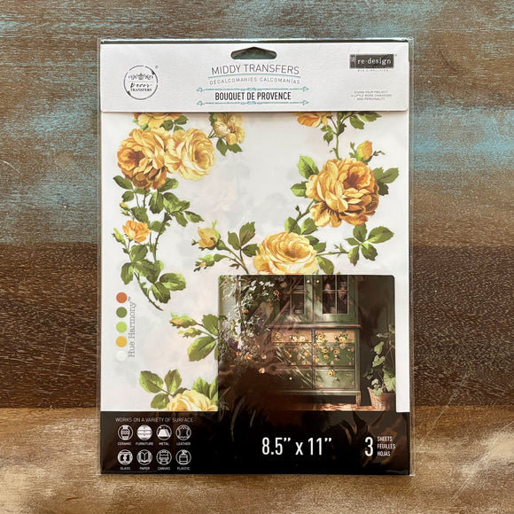 A package of ReDesign with Prima's Bouquet de Provence middy rub-on transfers are against a wood background.